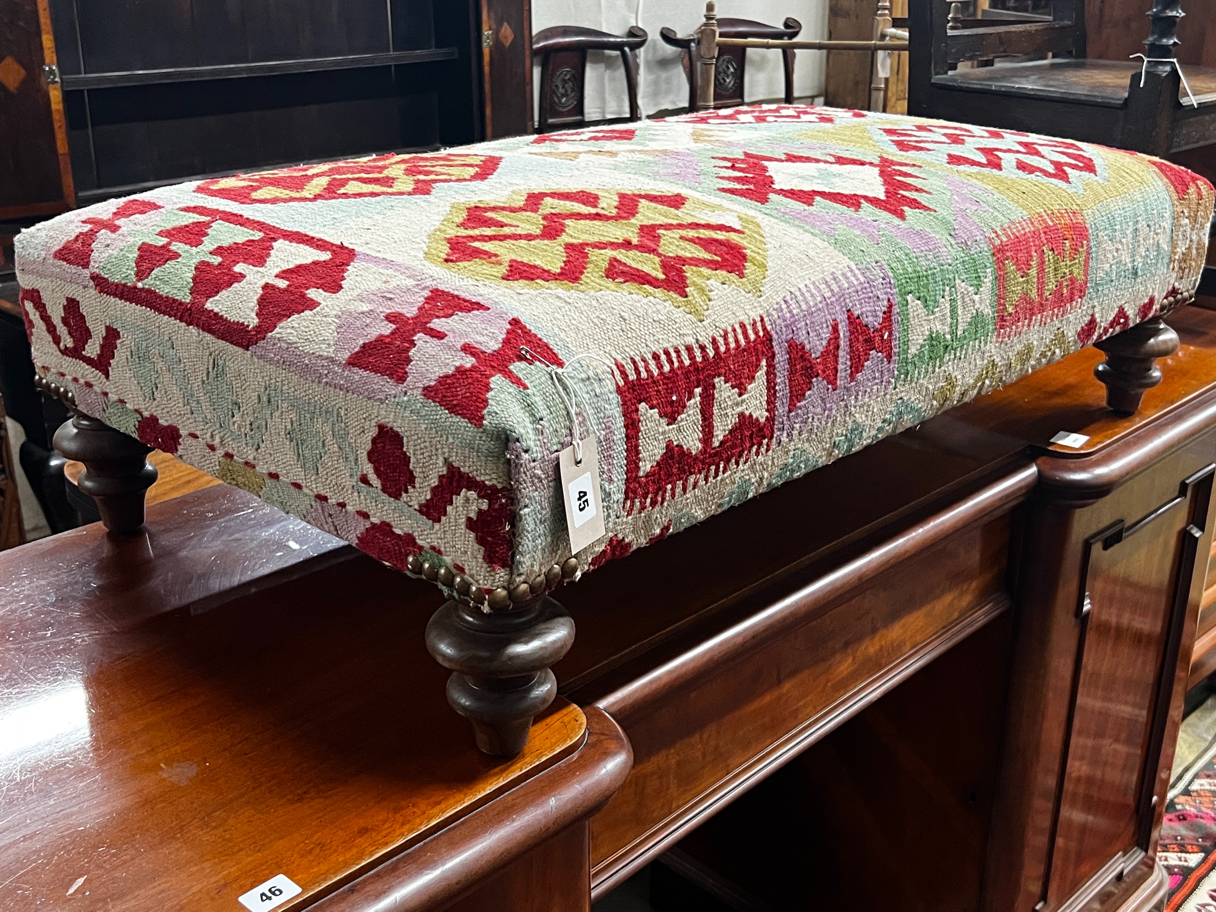 A large contemporary rectangular polychrome Kilim footstool on turned feet, length 108cm, depth 64cm, height 30cm